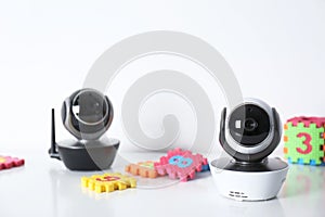 Modern CCTV security cameras and child puzzle on table against white background.