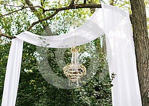 Modern celebration outdoor decoration. Destination elopement festive concept. Wedding arch made of white cotton fabric, decorated