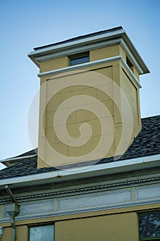 Modern chimney design with wooden pannels with metal pinacle with gray roof tiles on side of house or building in