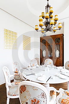 Modern Chinese restaurant VIP room with flowers on fabric decorated on chairs. wooden cabinet with porcelains inside.