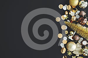 Modern christmas flat lay with golden baubles, confetti and decorations on black background. Seasons greeting card template with