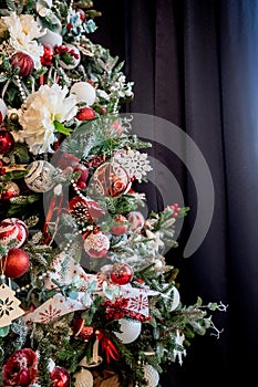 Modern christmas tree, decorated with vintage ornaments, ratan balls, burlap and tartan ribbons, wooden snowflakes, red