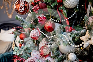 Modern christmas tree, decorated with vintage ornaments, ratan balls, burlap and tartan ribbons, wooden snowflakes, red