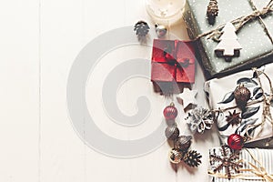 modern christmas wrapped presents with ornaments and cones on white wooden background top view, space text. merry christmas
