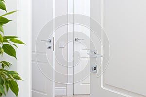 Modern chrome door handle on white door. Beautiful interior closeup