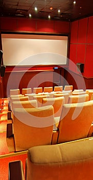 Modern cinema hall empty and beige comfortable seats, white cinema screen