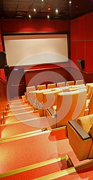Modern cinema hall empty and beige comfortable seats, white cinema screen