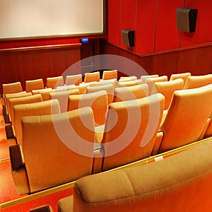 Modern cinema hall empty and beige comfortable seats, white cinema screen