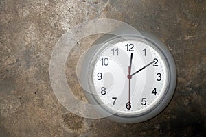 Modern circular clock hanging on old cement wall background