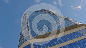 A modern city office building with a glass facade with a reflection of the sky. Skyscraper