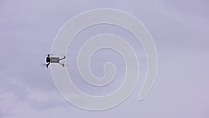 modern civilian quadcopter drone maneuvering in cloudy sky, view from ground