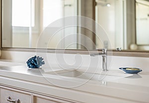 Modern and clean bathroom sink. Close-up of metal faucet and white sink in luxury bathroom interior with large mirror