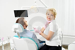 Modern clinic. Woman dentist looks into camera and holding tool