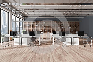 A modern co-working office interior with desks, computers, chairs, and a city view through large windows, in a contemporary design