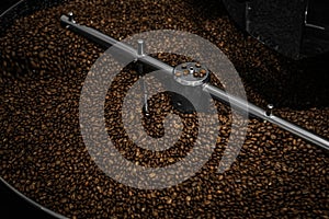 Modern coffee roaster machine with beans, closeup