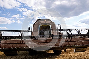 A modern combine harvester stands on the field during harvesting. Bottom view with a wide-angle lens on the hinged frame cutterbar