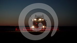 Modern combine harvester working on a wheat crop at night, front view