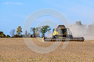 Modern combine harvesting grain crops in a field under autumnal blue sky