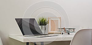 Modern comfortable office with open blank screen laptop computer with mock up frame
