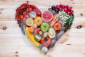 Modern composition of fresh healthy vegetables and fruits on the wooden table in the kitchen. Vegetarian vegan background.