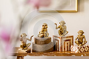 Modern composition of stylish accessories, decoration, flowers, gold monkey on the wooden bench at white living room interior.