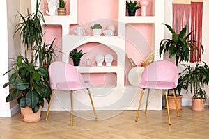 Modern composition of wabi sabi interior with arch shelf with home decoration and pink chair.