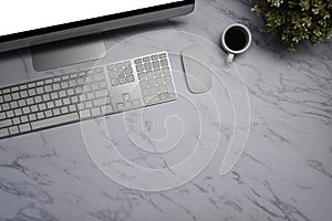Computer, coffee cup, wireless keyboard and mouse on marble background.