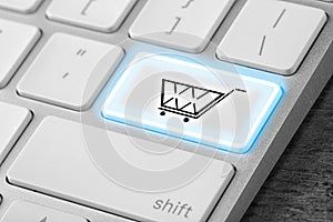 Modern computer keyboard with cart symbol on table, closeup. Internet shopping