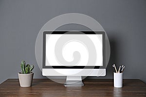 Modern computer monitor on table gray wall