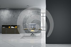 Modern concrete office interior with empty mock up place on wall, desktop and computer, other pieces of furniture and objects,