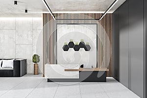 Modern concrete and wooden office lobby interior with reception desk, laptop, decorative plants and other items.
