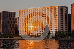 Modern condo apartment building on the riverbank in sunset light. Block of flats in complex of residential buildings