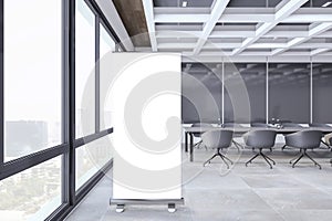 Modern conference room interior with empty white roll-up mockup banner, furniture, concrete flooring and window and city view. 3D