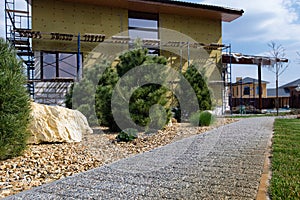 Modern  conifer tree garden design. House under construction.