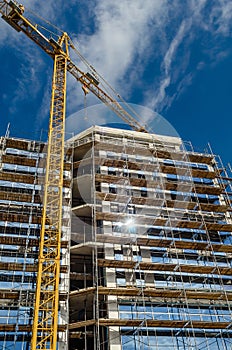 Modern construction finishing the facade of the house with glass window panels, scaffolding crane