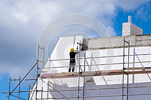 Man installing styrofoam sheets on house facade wall for thermal protection