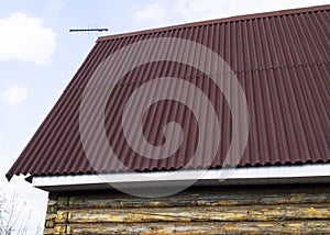 modern construction of the roof with red metal siding to a wooden house in the garden