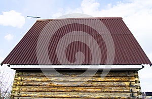 Modern construction of the roof with red metal siding to a wooden house in the garden