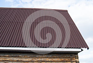 modern construction of the roof with red metal siding to a wooden house in the garden