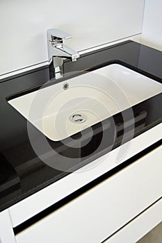 Modern and contemporary bathroom detail in a luxury home, black white sink and tap