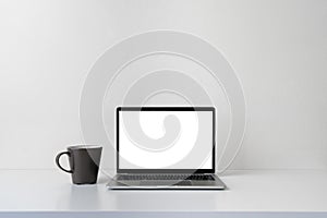 Modern contemporary workspace with blank screen laptop computer and coffee cup on office desk table on white background for copy