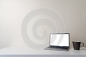 Modern contemporary workspace with blank screen laptop computer and coffee cup on office desk table on white background for copy