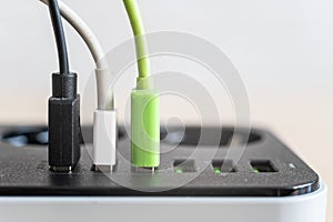 Modern convenient multi-port usb charger for devices. Close-up of multi-colored cables in a power outlet. Macro. pluged
