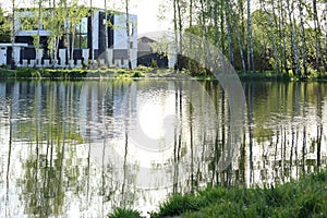 Modern cottage near lake in spring. Tree and grass. Nature and seasons. High quality photo.