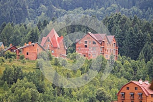 Modern cottages on slopes of forested mountains