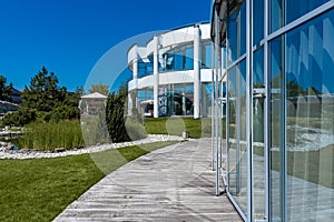 Modern country mansion and landscaped green garden with patio on sunny summer day