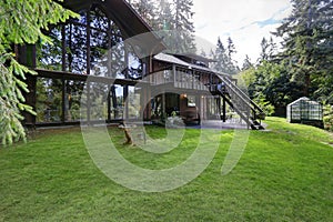 Modern countryside wooden house with big mirrored windows.