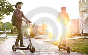 Modern couple using electric scooter in city park - Milenial students riding new ecological mean of transport - Green eco energy