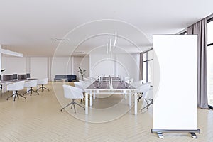 Modern coworking office interior with empty white roll up banner, furniture, equipment and other items in daylight. Mock up, 3D