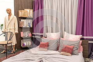 Modern cozy bedroom with a double bed, pillows and a blanket. A store selling beds and sleeping accessories. Mannequin in modern